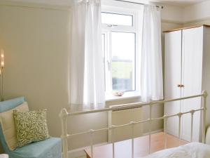 1 dormitorio con cama, ventana y silla en Tregatta Terrace en Tintagel