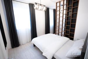 een slaapkamer met een wit bed en een raam bij RCity Apartament 4 in Boekarest