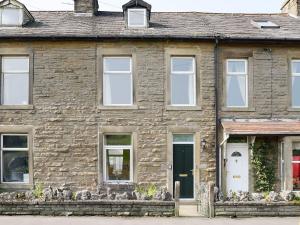 una casa de piedra con una puerta y ventanas negras en Three Peaks House en Horton in Ribblesdale