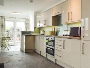a kitchen with white cabinets and a stove top oven at Three Peaks House in Horton in Ribblesdale