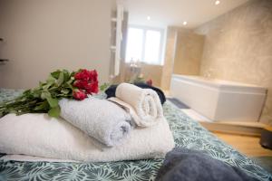 a pile of towels and a bouquet of roses on a bed at ODYSSEE l'expérience commence ici JACUZZI in Saint-Jean-Bonnefonds