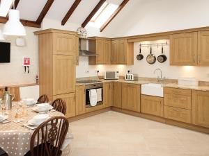 a kitchen with wooden cabinets and a table with chairs at The Barn in Tickton
