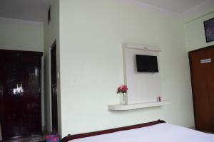 Hotel New Era في Butwāl: غرفة نوم مع سرير وتلفزيون على الحائط