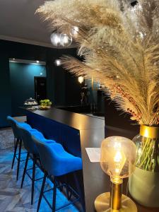 a bar with blue stools and a table with a lamp at Hotel Rumor in Budapest