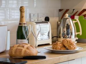 uma mesa com pão e uma garrafa de vinho e um prato de croissants em Sea Glimpse em Whitby