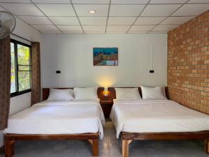 a room with three beds and a brick wall at Coconut Bungalow in Nai Yang Beach