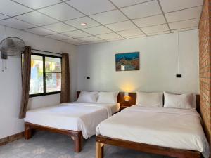 2 camas en una habitación con paredes blancas en Coconut Bungalow, en Nai Yang Beach