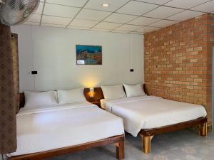 a room with two beds and a brick wall at Coconut Bungalow in Nai Yang Beach