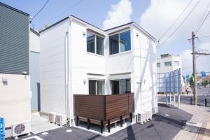 une maison blanche avec un banc dans une rue dans l'établissement Rakuten STAY HOUSE x WILL STYLE Matsue 101, à Matsue