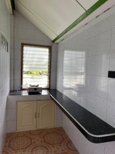 una pequeña cocina con encimera y ventana en Coconut Bungalow, en Nai Yang Beach