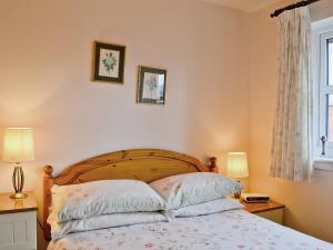 a bedroom with a bed with two lamps and a window at Glenrothay in Aviemore