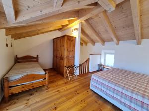 two beds in a room with wooden floors and wooden ceilings at Coccole nel fienile in Levico Terme