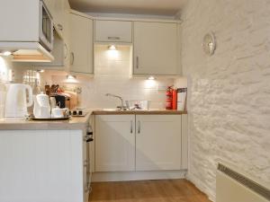 a kitchen with white cabinets and a counter top at Dovecote-tnq in Camelford