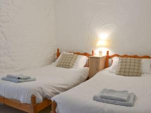 two twin beds in a room with a lamp and towels at Dovecote-tnq in Camelford