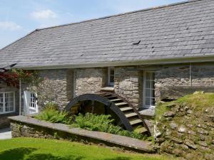 an old stone house with a spiral staircase in front of it at Dovecote-tnq in Camelford