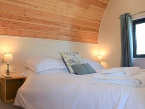 a bedroom with a white bed with a wooden ceiling at The Den - Uk32365 in Ellingham