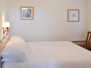 StokeinteignheadにあるPalm Treeの壁に2枚の絵が飾られたベッドルームの白いベッド1台