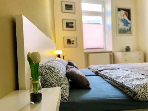 1 dormitorio con 1 cama con un jarrón de flores sobre una mesa en Kamoro, en Trier