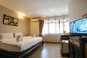 een slaapkamer met een bed en een flatscreen-tv bij Kamala's Boutique Guesthouse in Chiang Mai