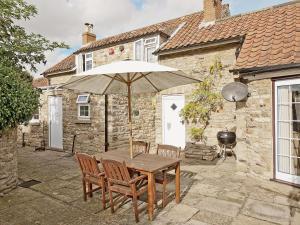 a wooden table with an umbrella in front of a building at Shaws Cottage in Thornton Dale