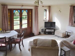 a living room with a table and a tv at Heathfield Lodge in Bransgore