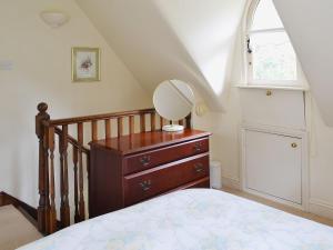 a bedroom with a bed and a dresser with a mirror on it at Heathfield Lodge in Bransgore