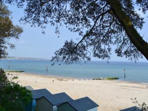 a beach with a house on the sand and the ocean at Heathfield Lodge in Bransgore
