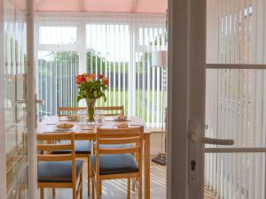 a dining room table with chairs and a vase of flowers at Seashore Hideaway in Newbiggin-by-the-Sea