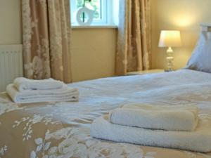 Una cama con toallas blancas encima. en Ty Main Cottage, en Newborough