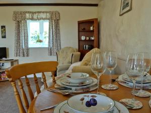 una mesa de comedor con vasos y platos. en Ty Main Cottage, en Newborough