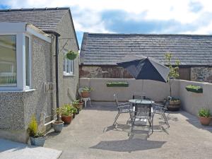 a table and chairs with an umbrella on a patio at Ty Main Cottage in Newborough