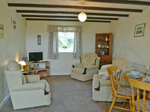 sala de estar con sillas, mesa y TV en Ty Main Cottage, en Newborough