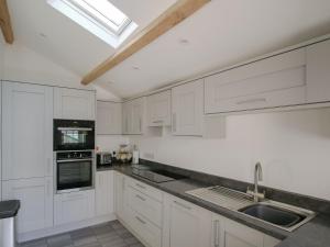 una cocina con armarios blancos y fregadero en Is Helen Cottage, en Caernarfon