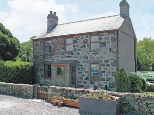 an old stone house with a fence in front of it at Is Helen Cottage in Caernarfon