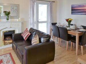 a living room with a leather couch and a dining room table at Seacroft in Cromer