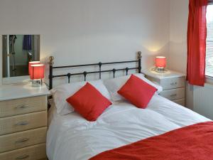 a bedroom with a bed with two red pillows at Seacroft in Cromer