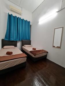 two beds in a room with blue curtains at Amilite Heritage Villa in George Town