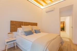 a white bedroom with a white bed with blue pillows at Apartamento Cetti Meriem in Granada