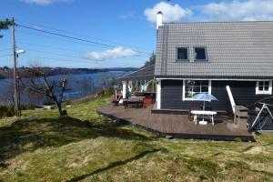 a house with a wooden deck next to a body of water at Topfloor Apartment Separate Entranc Nice view Stord in Fitjar