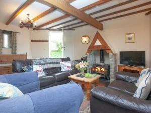 a living room with leather couches and a fireplace at The Roundhouse - Tbe in Crackington Haven