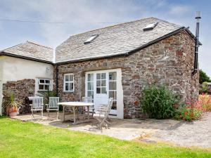 a stone cottage with a table and chairs in front of it at The Roundhouse - Tbe in Crackington Haven