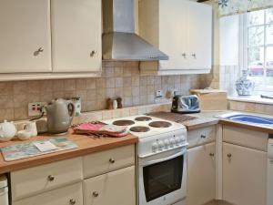 a kitchen with white cabinets and a stove top oven at Graig in Beaumaris