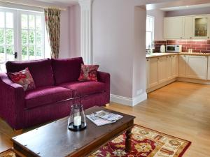 sala de estar con sofá púrpura y mesa en Roseburn Cottage en Moffat