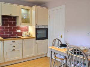 a kitchen with white cabinets and a table with chairs at Roseburn Cottage in Moffat
