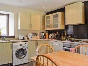 a kitchen with a washing machine and a table at Flowerdale Cottage in Lochgoilhead