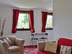 a living room with red curtains and a table at Flowerdale Cottage in Lochgoilhead