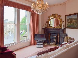 ein Wohnzimmer mit einem Sofa, einem TV und einem Spiegel in der Unterkunft The Savoy in Buxton