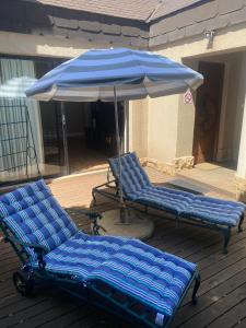 duas cadeiras azuis e um guarda-sol num deque em The Cottage em Somerset West