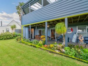 een huis met een blauw huis met een tuin bij 12 on Hilldale - Kuaotunu Holiday Unit in Whitianga