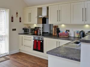 a kitchen with white cabinets and a stove top oven at Wheatsheaf Cottage in Nun Monkton